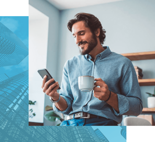 eine Person im Jeanshemd hält eine Kaffeetasse und schaut lächelnd auf ein Smartphone